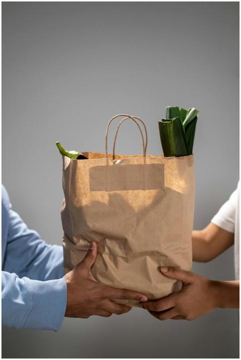 Close-up of hands exchanging a brown paper grocery