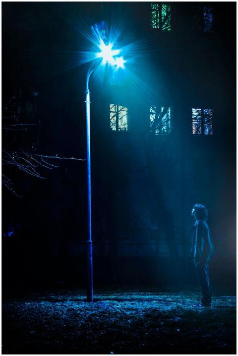 Silhouetted man under a bright streetlight at nigh