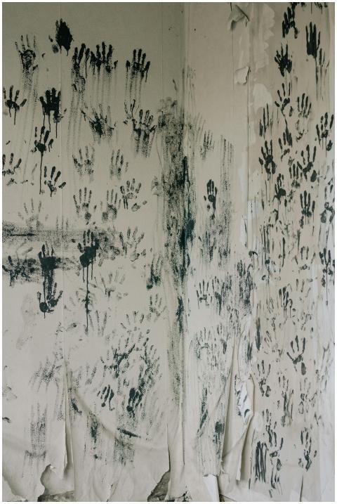 Mystical handprints cover a peeling wall, creating