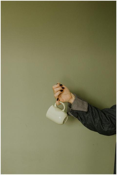 A stylish ceramic mug held by a woman's hand with