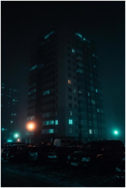 A foggy night scene with an illuminated skyscraper