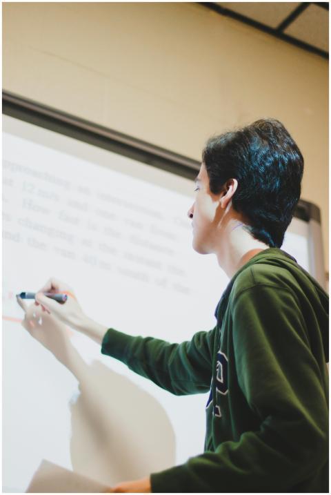 A student writing on a whiteboard indoors, capturi