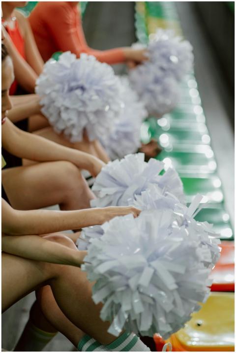 A group of cheerleaders holding pom poms while sit