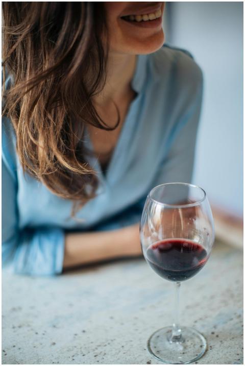A woman in a blue shirt smiling and enjoying a gla