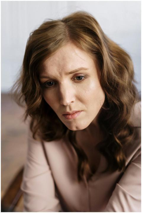 A woman with curly hair in deep thought, indoors,
