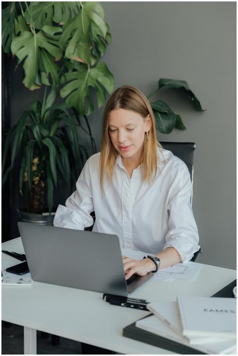 Focused young woman working on a laptop in a styli