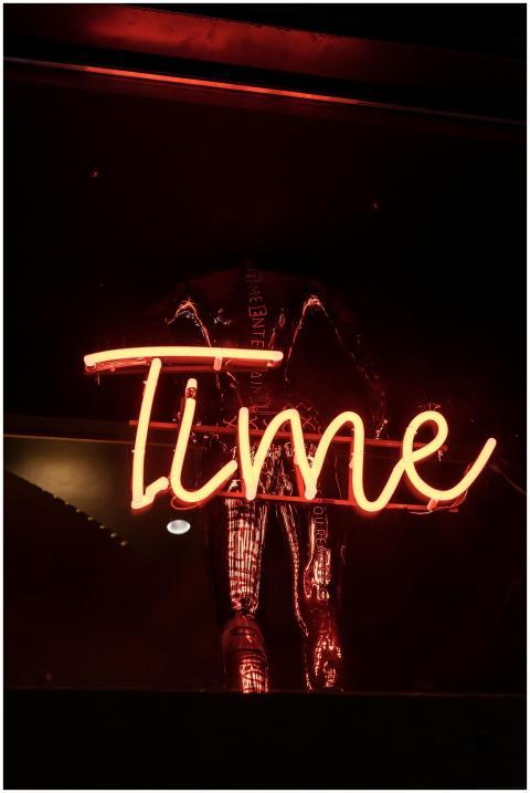 Vibrant neon 'Time' sign glowing warmly against a