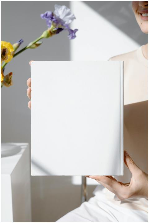 Minimalist blank book cover held in a bright room