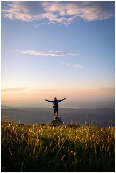 Silhouette of a hiker standing on a mountain peak,