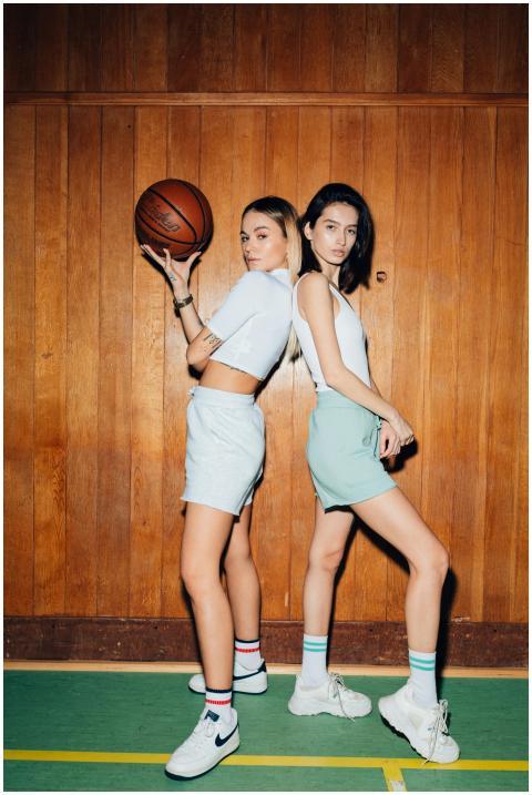 Two stylish young women posing indoors with a bask