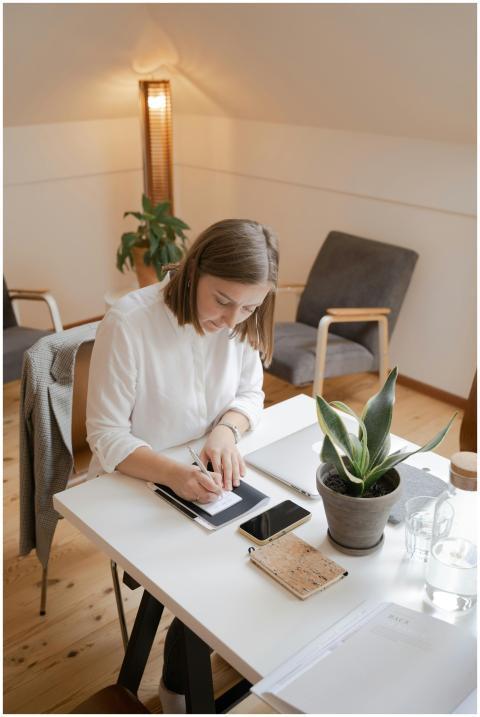 Woman in white long sleeves writing at desk in wel