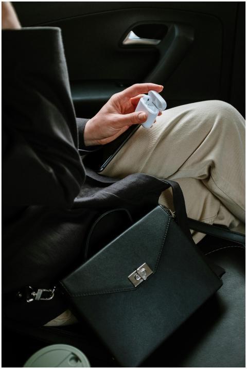 A woman with earbuds and a handbag inside a vehicl