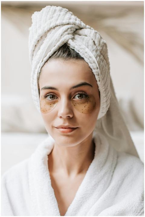 Woman in bathrobe applying skincare treatments wit