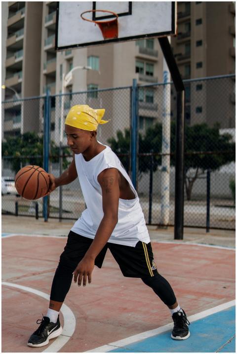 Young man dribbling a basketball on an outdoor cou