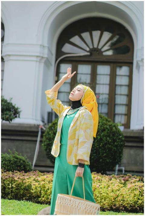A woman in colorful traditional attire poses outdo