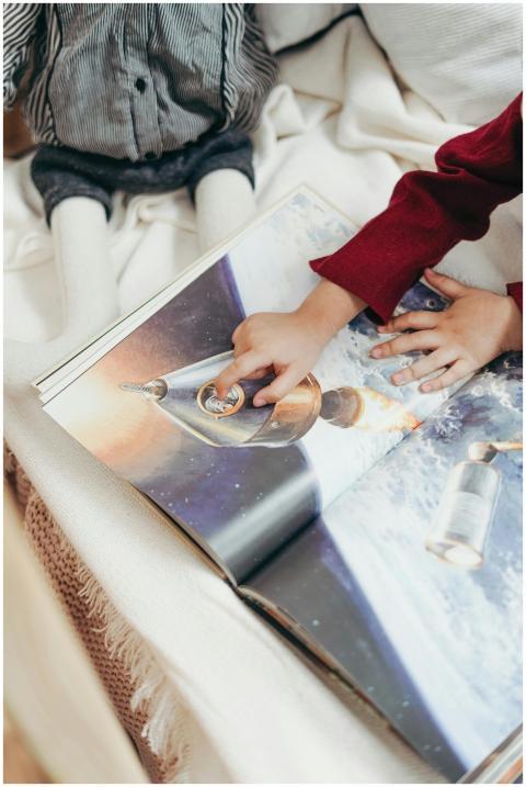 A child's hand pointing at a rocket illustration i