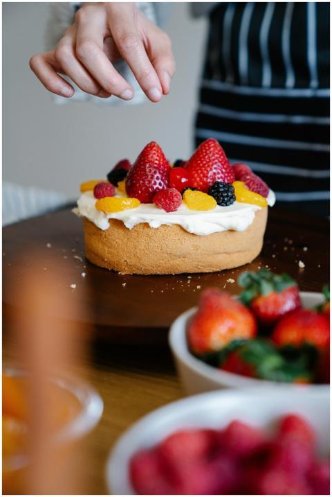 Close-up of a fresh fruit-topped cake being finish
