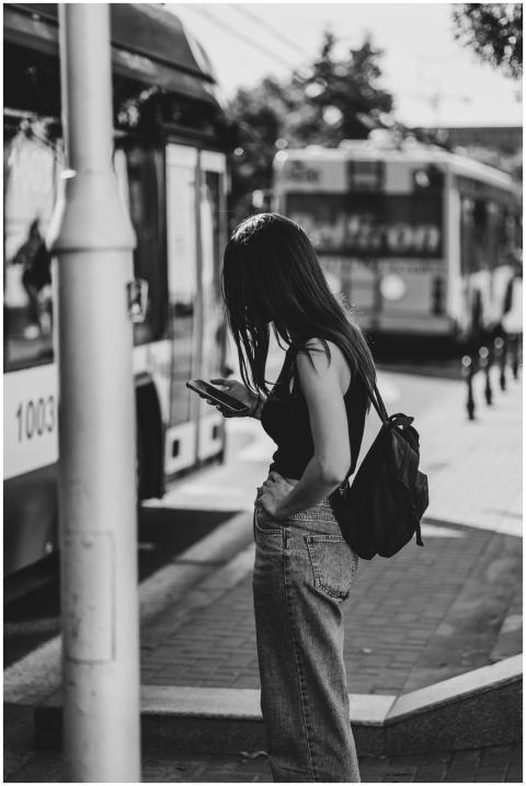 Black and white photo of a woman at a city bus sto