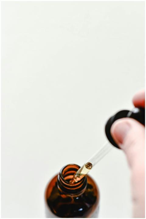 Close-up of a glass dropper with liquid above an a