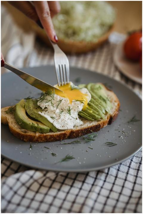 A close-up of avocado toast topped with egg, garni