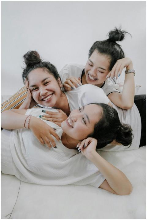 Three young women laughing and embracing each othe