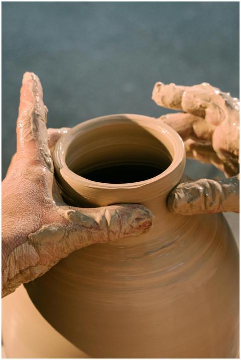 Close-up of hands molding a clay pot, highlighting
