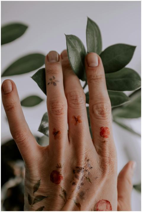 Close-up of a tattooed hand touching green leaves,