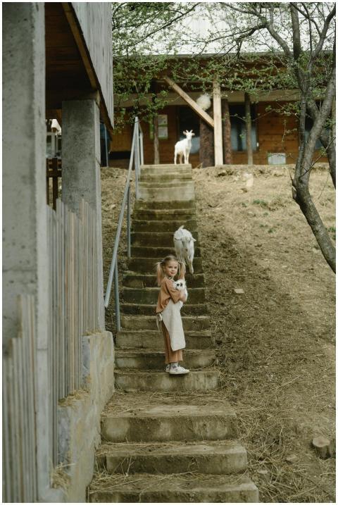 A young girl holding a goat on a rustic outdoor st