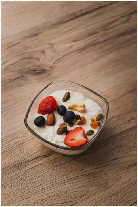 A bowl of yogurt topped with fresh strawberries, b