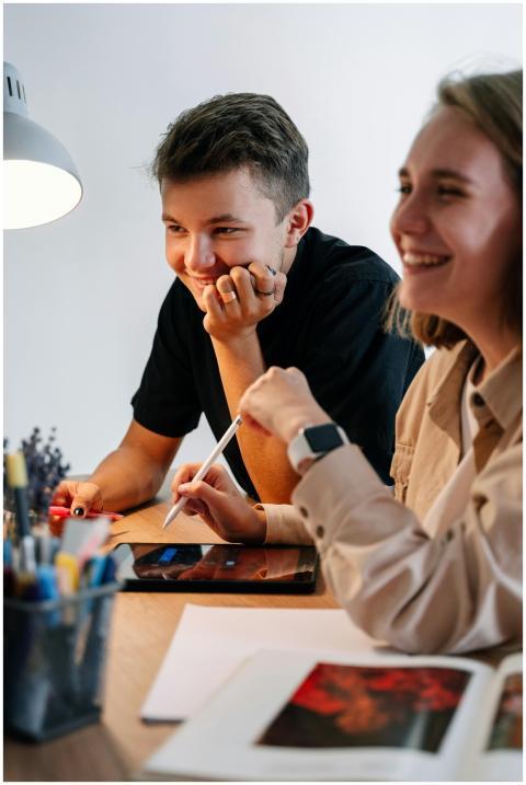 Two young adults smiling and collaborating using a