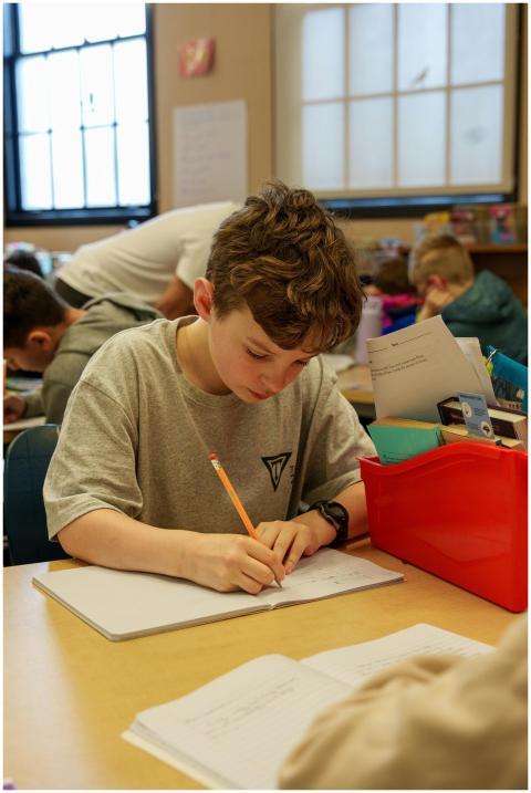 Young student concentrating on his writing task in