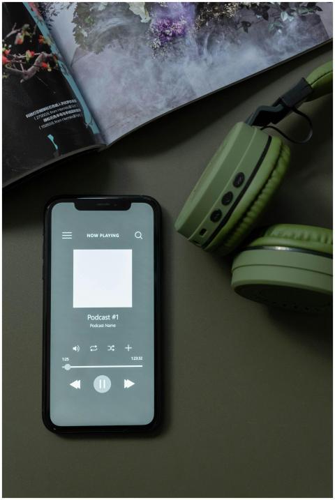 Modern smartphone and green headphones next to a m