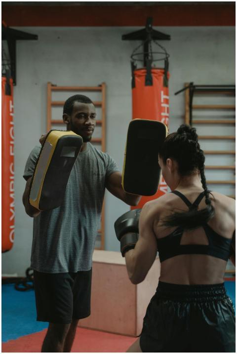 A woman engaged in boxing training with a trainer