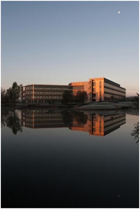 A modern office building reflected in a calm lake
