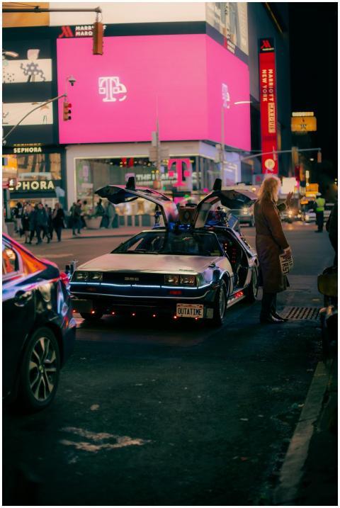 A classic DeLorean DMC car parked on a bustling ci