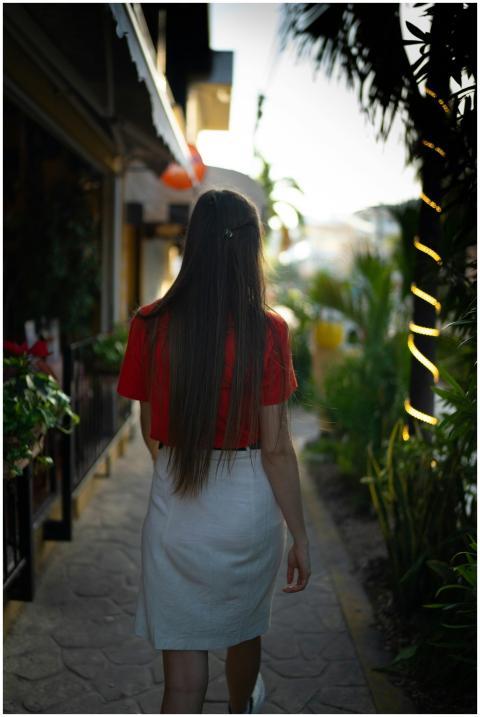 Back view of a woman with long hair walking on a s