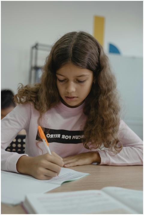 Focused young girl in a classroom setting, writing