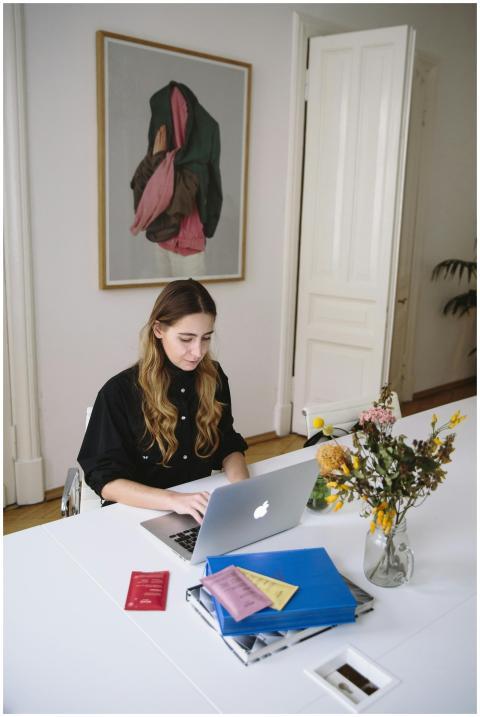Young woman using a laptop at a desk with document