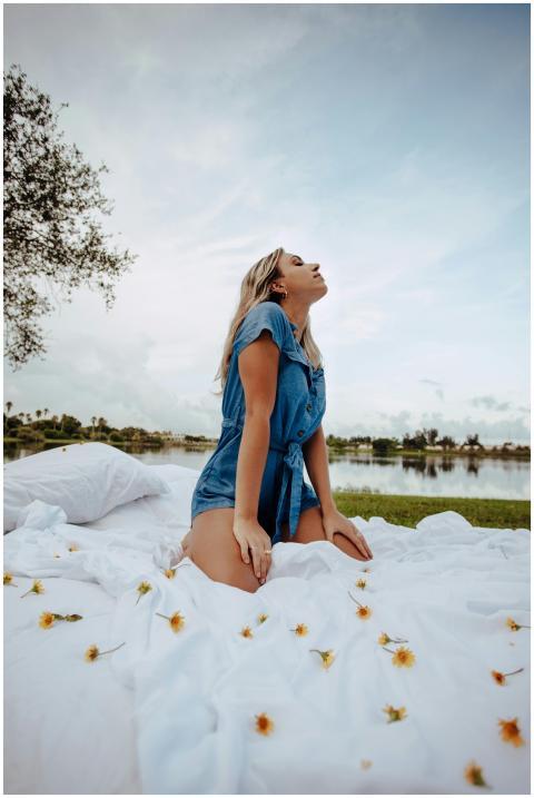 Woman in blue jumpsuit poses elegantly on a white