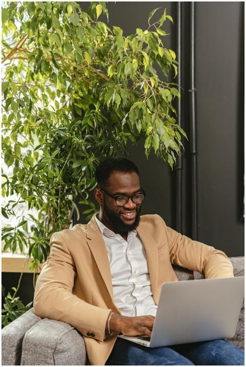 Confident man in casual blazer using laptop on sof
