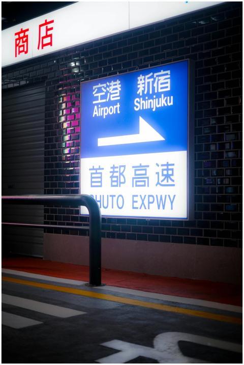 A night view of a Shinjuku highway sign pointing t