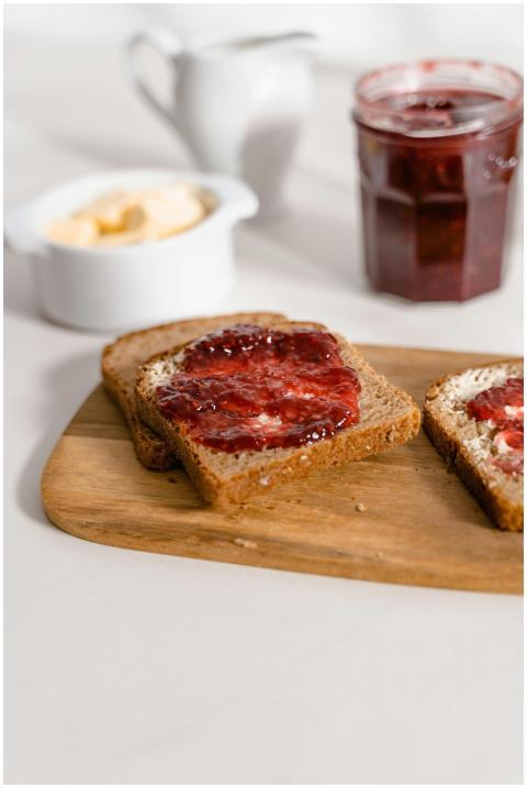 Two slices of toast with strawberry jam on a woode