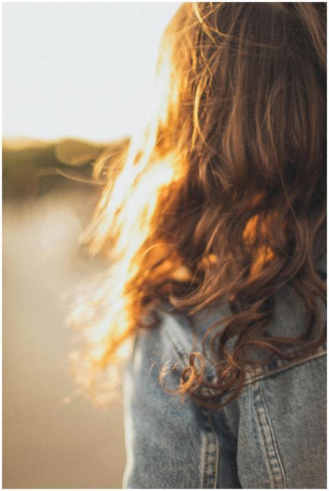A woman in a denim jacket with long, wavy hair ill
