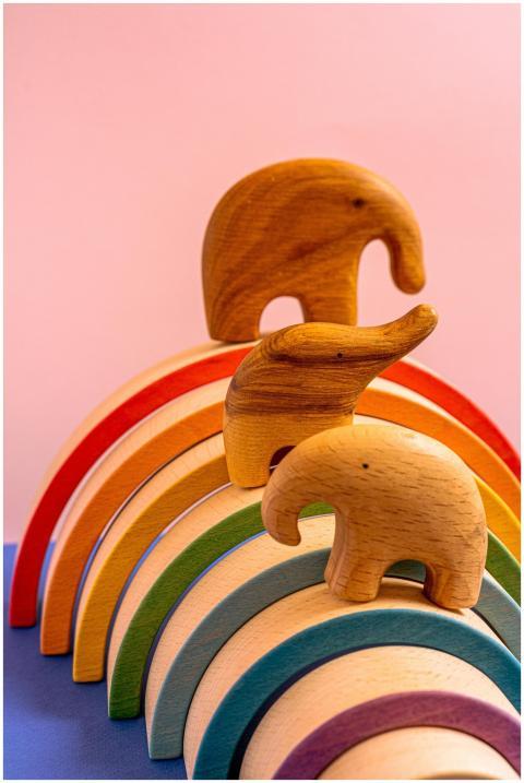 Vibrant wooden elephant figurines on a rainbow arc