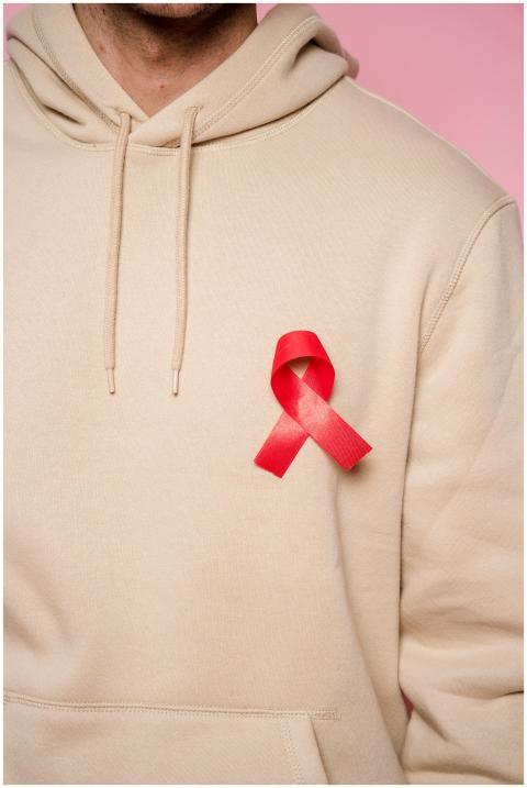 A close-up of a red ribbon on a beige hoodie symbo