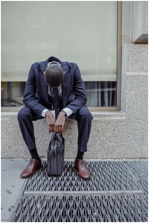 A businessman in a suit sits with his head down, e