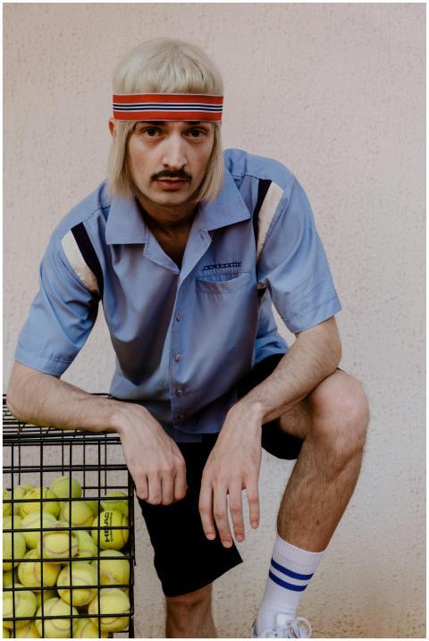 Man in retro tennis outfit with headband and tenni