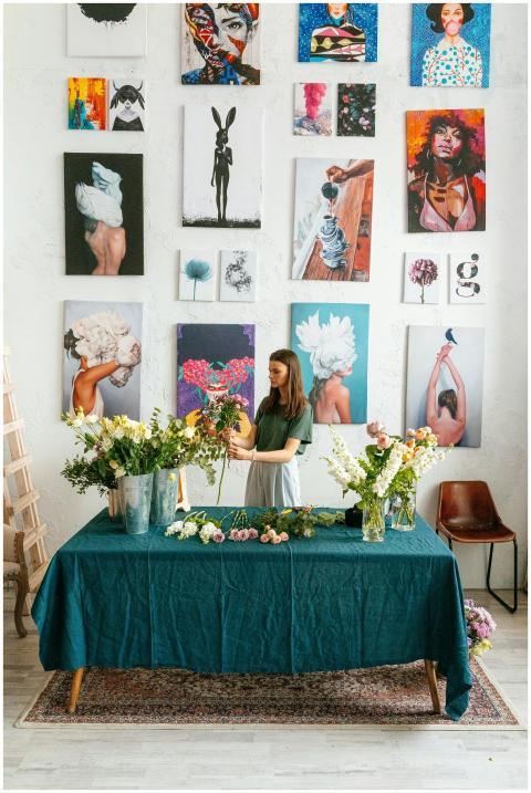A woman arranges flowers in a vibrant art studio w