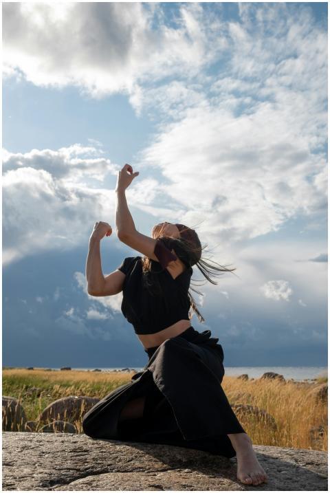 A person dances energetically on a rock under a vi