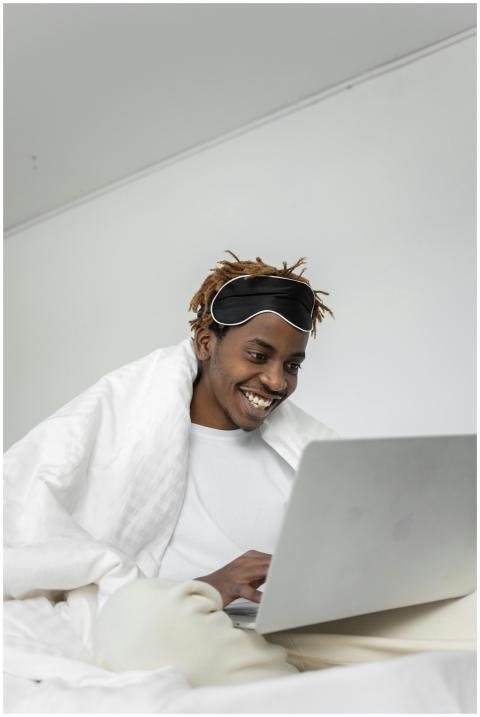 A smiling young man sitting in bed, engaging with
